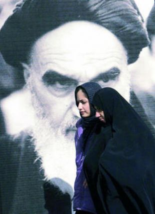 D&uacute;as mulleres pasan por diante dunha imaxe de Khomeini en Teheran