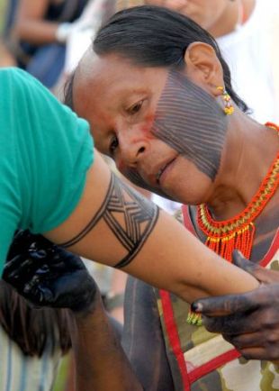 Ind&iacute;xena da etnia Caiap&oacute; ax&uacute;dalle a pintarse a un participante na marcha inaugural do FSM