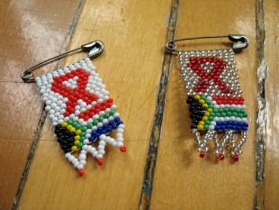 Os lazos vermellos contra a sida, por riba da bandeira de Sud&aacute;frica / Flickr: mvcorks